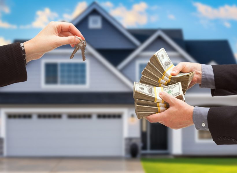 Real Estate Agent Handing Over House Keys for Stacks of Money in Front of New House.